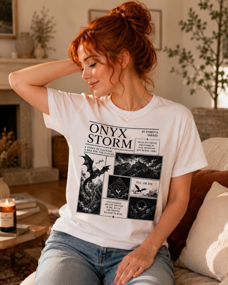 May include: White t-shirt with the text "ONYX STORM" and illustrations of a dragon, castle, and other fantasy elements. The shirt also includes the text "A STORY OF COURAGE, A WAR FOR THE FUTURE" and "FLY...OR DIE."