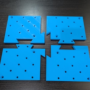 May include: Four blue plastic jigsaw pieces with a grid of holes. The pieces fit together to form a larger square.