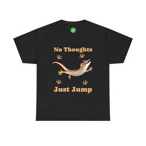 May include: Black t-shirt featuring a cartoon gecko with the text "No Thoughts Just Jump". The gecko is tan and brown with a white belly, and is jumping. The text is in a tan color.