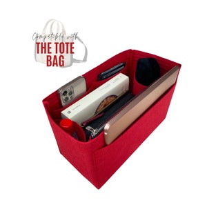 May include: Red felt tote bag organizer with multiple pockets and compartments. The organizer is filled with various items, including a phone, a book, a wallet, and a tablet. The text "Compatible with THE TOTE BAG" is visible in the top left corner of the image.