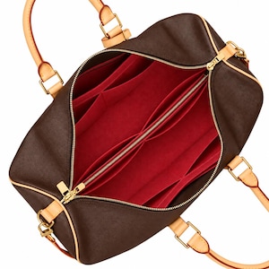 May include: A dark brown handbag with a bright red interior organiser insert. The bag features light tan leather handles attached with gold-tone metal hardware. The interior is divided into multiple compartments with a central zippered pocket.