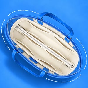 May include: A bright blue tote bag with a cream-colored interior organizer insert. The insert features multiple open compartments and a central zippered pocket. White dashed arrows indicate the rounded shape of the bag's opening.