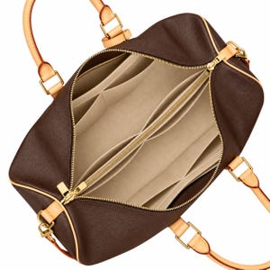 May include: A dark brown handbag with a beige felt interior organiser insert featuring multiple compartments and pockets. The bag has light tan leather handles, gold-tone metal hardware, and a top zip closure that is partially open.