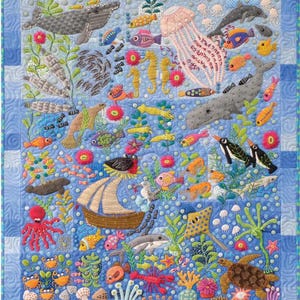May include: A colorful embroidered quilt depicting an underwater scene with various sea creatures, including fish, seahorses, a whale, a jellyfish, a turtle, a crab, and a ship. The quilt is made on a blue background with white squares.