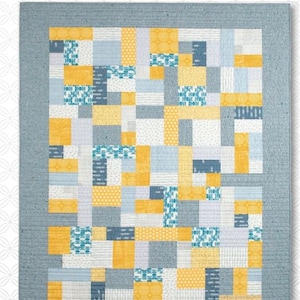 May include: A quilt pattern called "Yellow Brick Road" by Atkinson Designs. The pattern features a patchwork design with yellow, blue, and white squares. The quilt is framed with a blue border.
