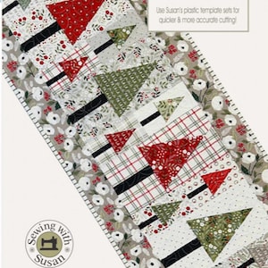 May include: A table runner featuring a Christmas tree design with red, green, and white fabrics. The runner is 18 1/2 inches by 45 1/2 inches and has a white floral border. The text "Fa la la Forest" is printed on the bottom of the runner.