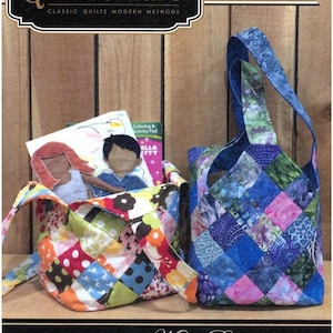 May include: Two quilted tote bags, one with a colorful patchwork design and the other in blue tones, are displayed. The bags are part of a quilting project kit, with the "Quiltsmart" logo visible, along with text that reads "Easy! Fast! Smart!" and "Midi Bag".