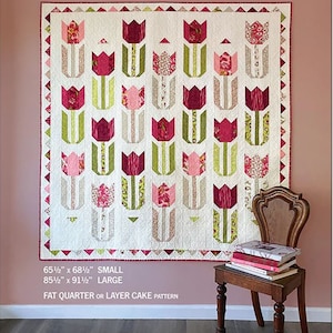 May include: A quilt pattern featuring a tulip design with pink, red, and green fabric. The pattern is called "Tulip Season" and is available in two sizes: 65 1/2 inches by 68 1/2 inches and 85 1/2 inches by 91 1/2 inches. The pattern is designed by Robin Pickens.
