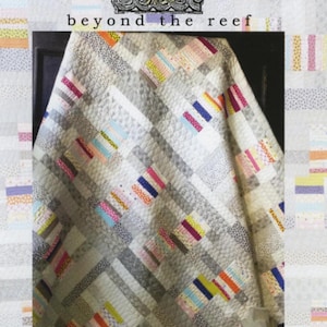 May include: A handmade quilt with a geometric design. The quilt features a light gray background with colorful rectangular patches in shades of pink, blue, yellow, and green. The words "beyond the reef" and "mochi" are visible.