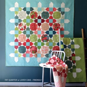 May include: A large, colorful quilt with a geometric design, featuring red, green, and blue patterns. The word "Picket" is at the top. A smaller quilt and a quilt on a chair are also visible. The text "FAT QUARTER or LAYER CAKE - FRIENDLY" is at the bottom.