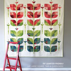 May include: A large, rectangular quilt with a floral design. The quilt features stylized red and green flowers on a white background. The text "BEANSTALK" is at the top. A red step ladder leans against the wall. The quilt is fat quarter-friendly.