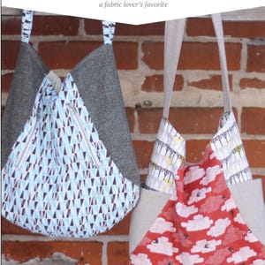 May include: Two tote bags hanging on a brick wall. The bag on the left is gray with a blue and white geometric pattern. The bag on the right is beige with a red and white cloud pattern. The text "241 TOTE" and "a fabric lover's favorite" is above the bags. The text "noodlehead" is below the bags.