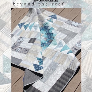 May include: A quilt with a patchwork design featuring a variety of shades of blue, gray, and white. The quilt is folded and lying on a wooden surface. The text "beyond the reef homeward" is printed on the image.