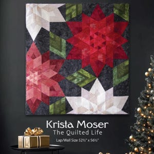 May include: A Crimson Christmas quilt featuring red, white, and green starburst designs. The quilt is 52.5 x 56.5 inches. The image also includes wrapped gifts and a Christmas tree, creating a festive holiday scene.