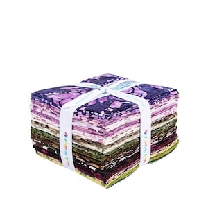 May include: A stack of fabric squares in various colors, including purple, green, and pink, is tied with a white ribbon. The fabric has floral patterns. The ribbon has the text "colorfully" printed on it.