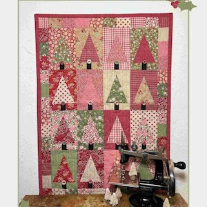 May include: A quilt pattern titled Christmas Memories #359 measuring 14 1/2 inches by 20 1/2 inches. The quilt features a grid of rectangular blocks, each containing a triangular tree shape in various red, pink, and green floral or gingham fabrics.