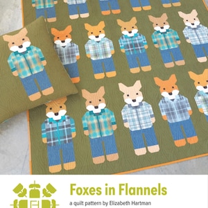 May include: A quilt and pillow featuring a repeating pattern of foxes wearing flannel shirts and jeans. The foxes are in various plaid patterns and colors, set against a green background. The text "Foxes in Flannels" is at the bottom.