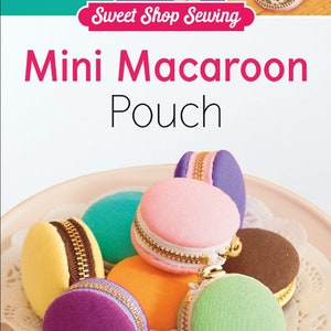 May include: A collection of colorful mini macaron pouches with zipper closures, displayed on a pink plate. The pouches are in various colors, including pink, yellow, purple, and green. The image also includes the text "Mini Macaroon Pouch".