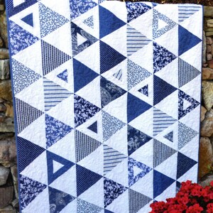 May include: A blue and white quilt with a geometric triangle pattern. The quilt features various blue patterns, including floral, striped, and polka dot designs, set against a white background. The words "Equal Rights" are at the top.