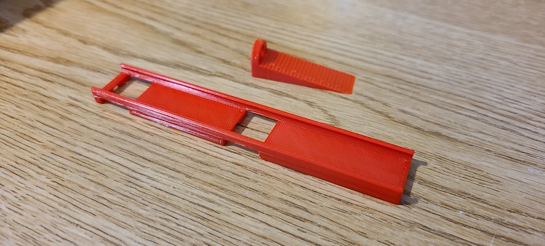 May include: A red plastic ramp with a small red plastic ramp on the side. The ramps are designed for use with toy cars.