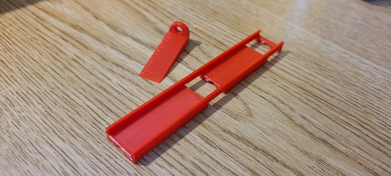 May include: A red plastic ramp with a smaller red plastic piece that fits into the ramp. The ramp has a slot in the middle.