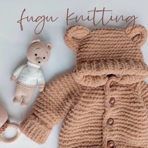 May include: A tan, hooded baby sweater with bear ears, wooden buttons, and matching mittens. A crocheted bear rattle and a crocheted bear doll are also in the image. The words "fugu knitting" are written in a brown script font.