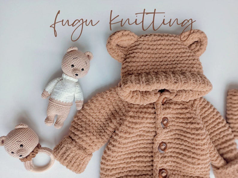 May include: A tan, hooded baby sweater with bear ears, wooden buttons, and matching mittens. A crocheted bear rattle and a crocheted bear doll are also in the image. The words "fugu knitting" are written in a brown script font.