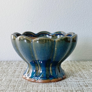 May include: A blue and green ceramic planter with a scalloped rim and a pedestal base.