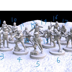 Op de afbeelding: Een verzameling onbeschilderde miniatuurfiguren van soldaten in gevechtshoudingen. De figuren staan in verschillende houdingen, sommige knielend, sommige staand en sommige die wapens richten. De sc&egrave;ne speelt zich af op een wit, getextureerd oppervlak.