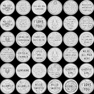 K&ouml;nnte beinhalten: Eine Sammlung silberfarbener, kreisf&ouml;rmiger Token mit verschiedenen Phrasen und Designs. Die Token enthalten Texte wie "I Love You", "Sunshine" und "Ghostie Girl". Der Hintergrund ist einfarbig schwarz.