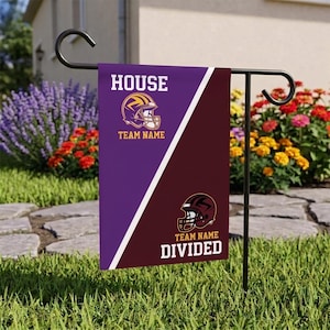 May include: A rectangular garden flag hanging on a black metal stand. The flag is split diagonally into purple and maroon sections. It features two football helmet graphics, the text HOUSE TEAM NAME, and the text TEAM NAME DIVIDED in white.
