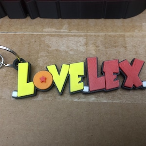 May include: A yellow, red, and orange keychain with the word "LOVELEX" and a small orange sphere with a red star on it.