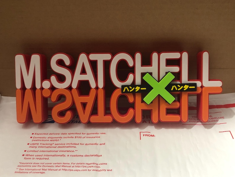 May include: A red and orange sign with the text "M. SATCHELL" and "W241CHET" in white letters. The sign also has a green "X" with the text "ハンター" in yellow on either side.