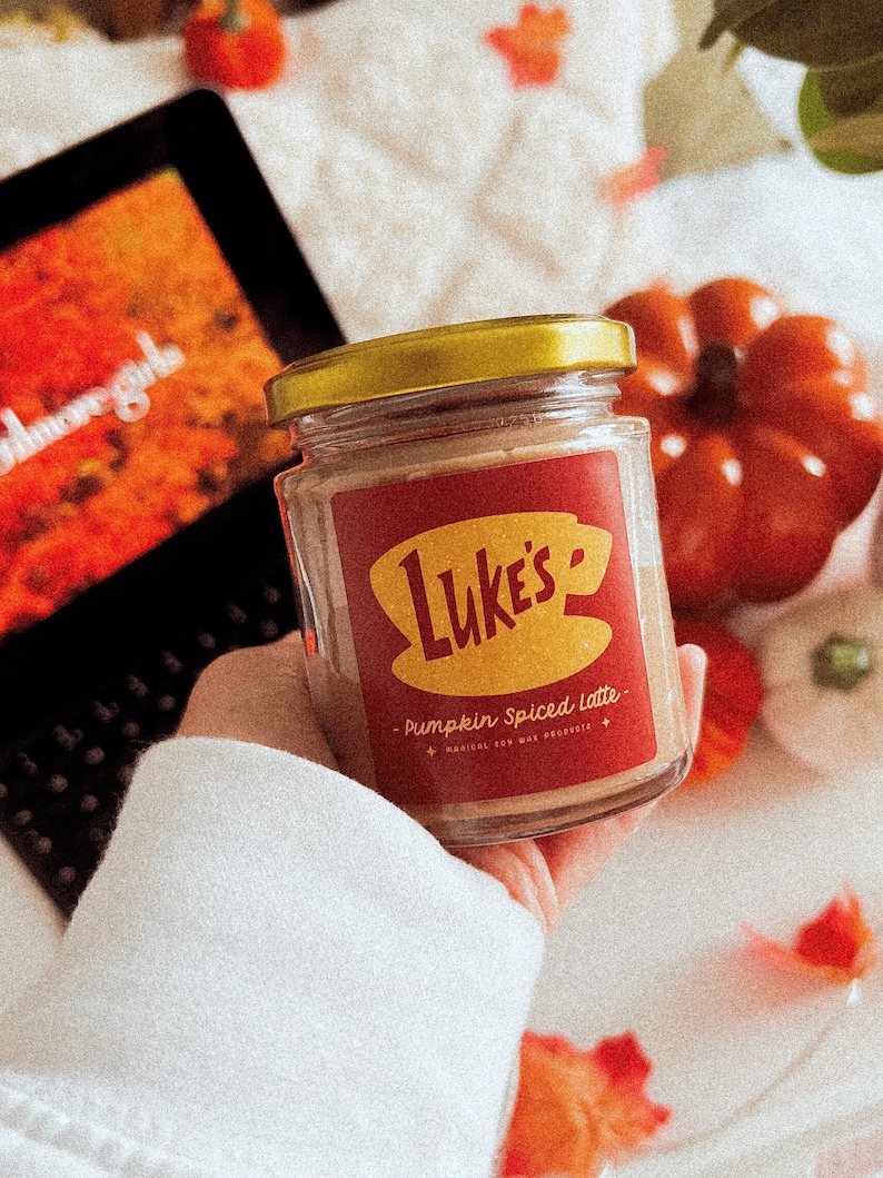 May include: A glass jar with a gold lid filled with a brown substance. The jar has a red and yellow label that says "Luke's" and "Pumpkin Spiced Latte".