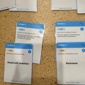 Peut inclure: Un ensemble de cartes éducatives blanches pour l'anesthésie et les soins périopératoires. Les cartes présentent des en-têtes bleus marqués Round 2, avec des indices textuels et des termes comme Moderate sedation, Naloxone et des descriptions.