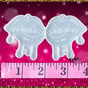 Pu&ograve; includere: Uno stampo in silicone trasparente a forma di due paia di labbra con un design a goccia. Lo stampo misura circa 10 cm di larghezza. Il testo "Resin Happy" &egrave; visibile in basso a destra.
