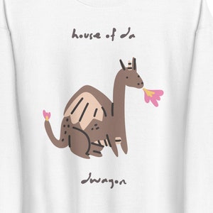 May include: White sweatshirt with a brown cartoon dragon wearing a crown and blowing a pink flower. The text "house of da dragon" is above the dragon and "dragon" is below the dragon.