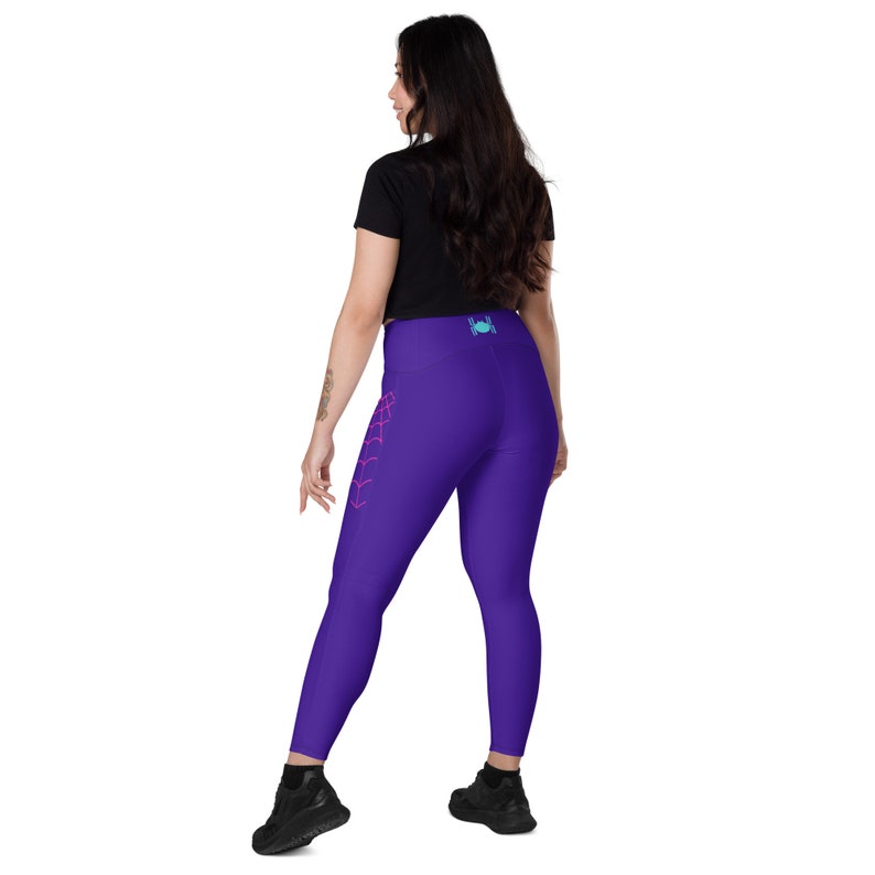 Puede incluir: Leggings moradas con un dise&ntilde;o de telara&ntilde;a de ara&ntilde;a rosa en la pierna izquierda. Las leggings tienen cintura alta y un peque&ntilde;o logotipo de ara&ntilde;a azul en la parte posterior.