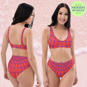 K&ouml;nnte beinhalten: Ein zweiteiliges Bikini-Set mit einer leuchtend roten Grundfarbe und einem sich wiederholenden blauen Spinnennetz-Muster. Das Set besteht aus einem Bikini-Oberteil mit Rundhalsausschnitt und breiten Tr&auml;gern sowie einer Bikini-Hose mit hoher Taille. Der Text lautet CHECK OUT MOODY SUNDAY ON ETSY.