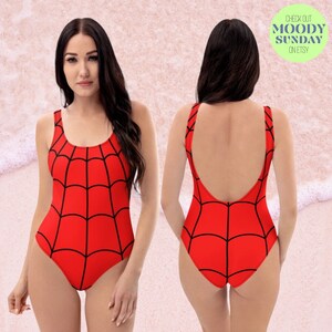 Puede incluir: Traje de ba&ntilde;o rojo con un dise&ntilde;o de telara&ntilde;a negra. El traje de ba&ntilde;o tiene un escote redondo y una espalda baja.