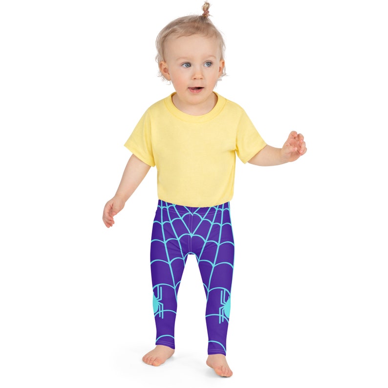 May include: A child wearing a yellow short-sleeved shirt and purple leggings with a blue spider web pattern.