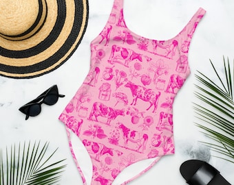 May include: Pink one-piece swimsuit with a cow and milk jug pattern. The swimsuit has a scoop neck and thin straps.