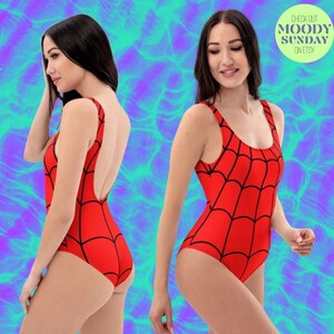 Puede incluir: Traje de ba&ntilde;o rojo con un dise&ntilde;o de telara&ntilde;a negra. El traje de ba&ntilde;o tiene un escote redondo y una espalda baja.