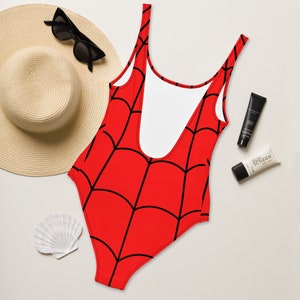 Puede incluir: Traje de ba&ntilde;o rojo con un patr&oacute;n de telara&ntilde;a negra. El traje de ba&ntilde;o tiene un escote redondo y tirantes finos.