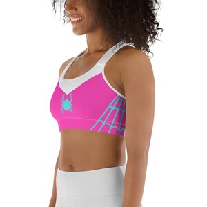 May include: Pink and white sports bra with a blue spider web design and a blue spider graphic.
