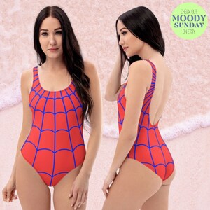 Może przedstawiać: Czerwony jednoczęściowy str&oacute;j kąpielowy z niebieskim wzorem pajęczyny. Str&oacute;j kąpielowy ma okrągły dekolt i niski tył.