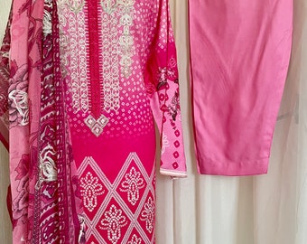 May include: A pink and white patterned dress with white embroidery and a matching pink shalwar. The dress has a round neckline and long sleeves. The shalwar is a pair of loose-fitting pants.