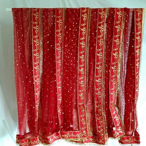 May include: Red sheer fabric with gold embroidered trim and sequins. The trim features the repeated phrase "قبول ہے" in Arabic script.