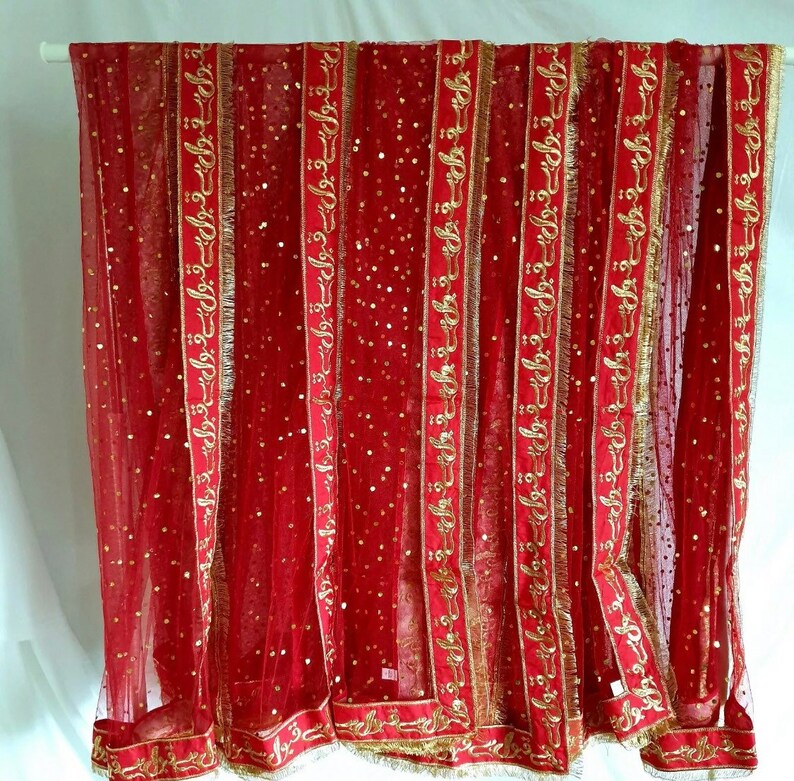 May include: Red sheer fabric with gold embroidered trim and sequins. The trim features the repeated phrase "قبول ہے" in Arabic script.