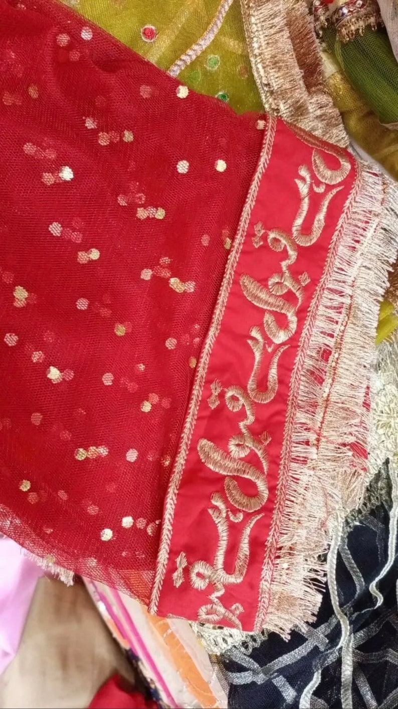May include: Red sheer fabric with gold sequins and a gold embroidered border. The border features a repeating pattern of a stylized flower.